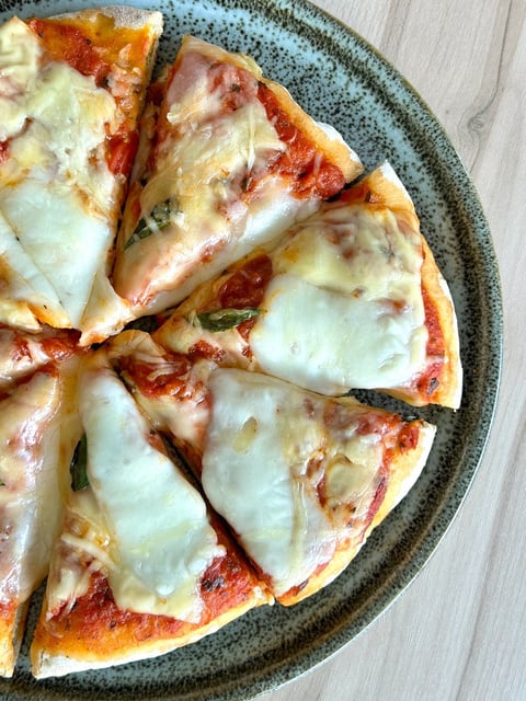 Sliced pizza with melted cheese and tomato sauce on a speckled gray plate