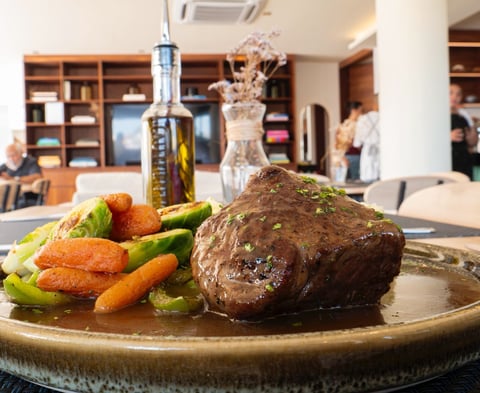 Plated beef steak with roasted carrots and green beans in an upscale restaurant setting